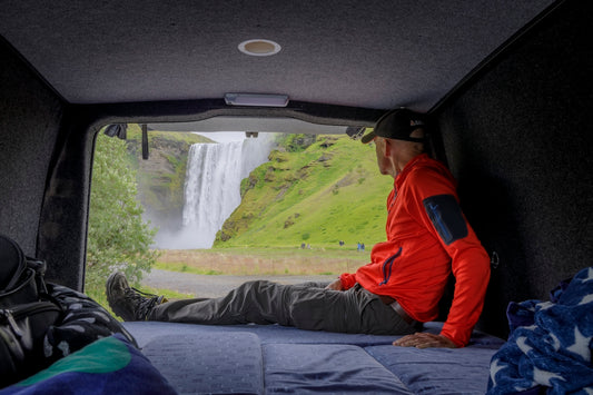 a man sitting in the back of a truck looking at a waterfall