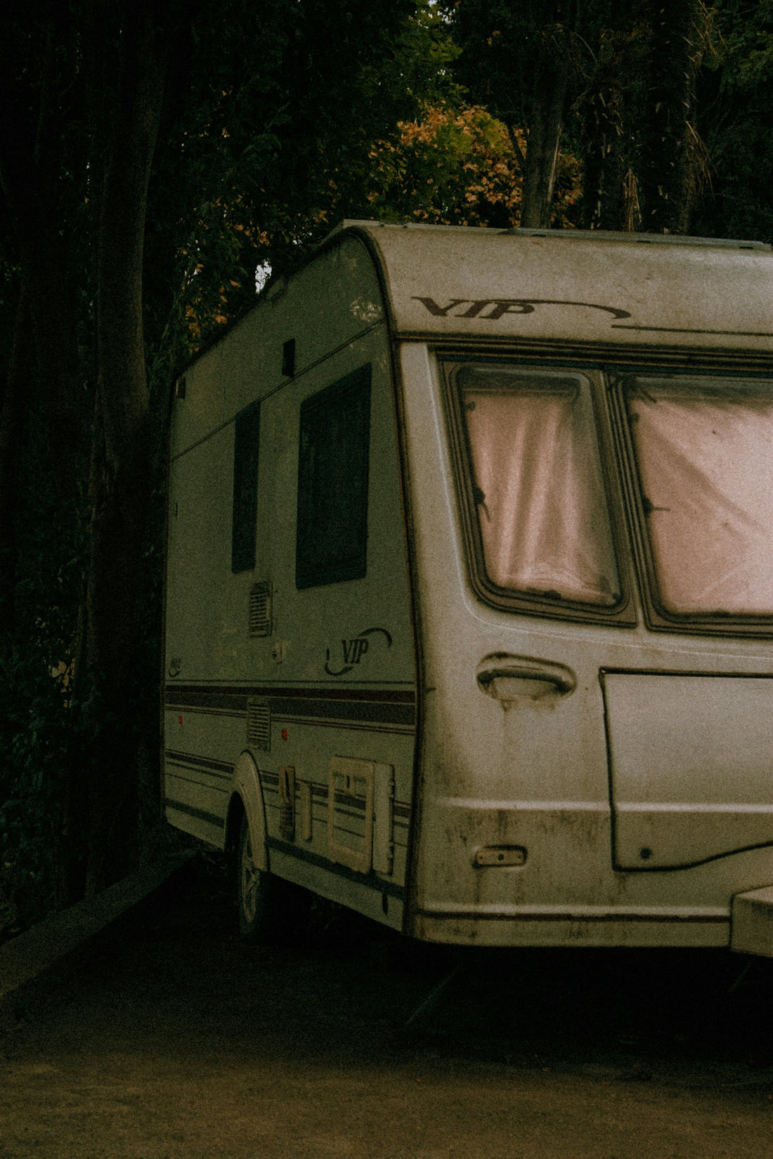 an old camper parked next to a tree