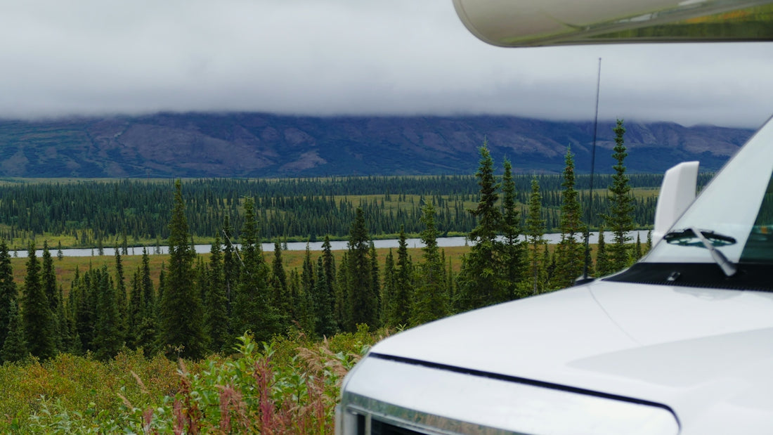 White camper van parked with forest and hills background