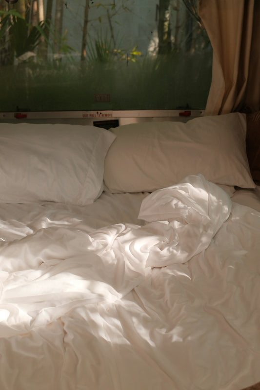 Unmade bed with white sheets and pillows.