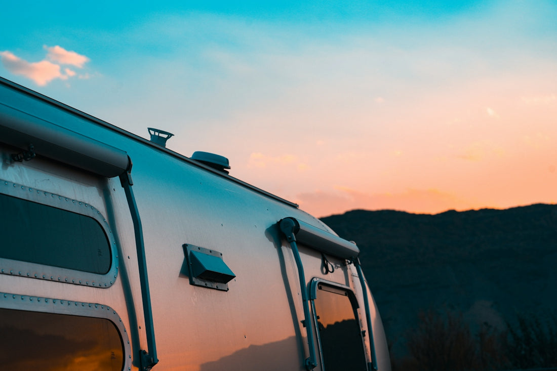 Silver travel trailer against a sunset sky
