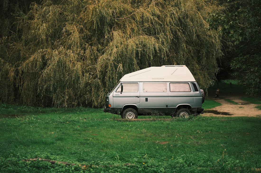 A silver camper van parked in a grassy field.