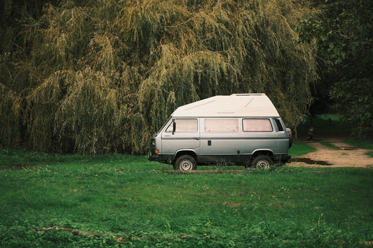 A silver camper van parked in a grassy field.