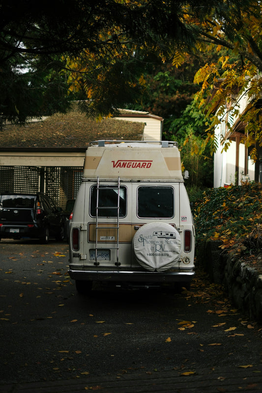 White camper van parked on a leaf-covered street.