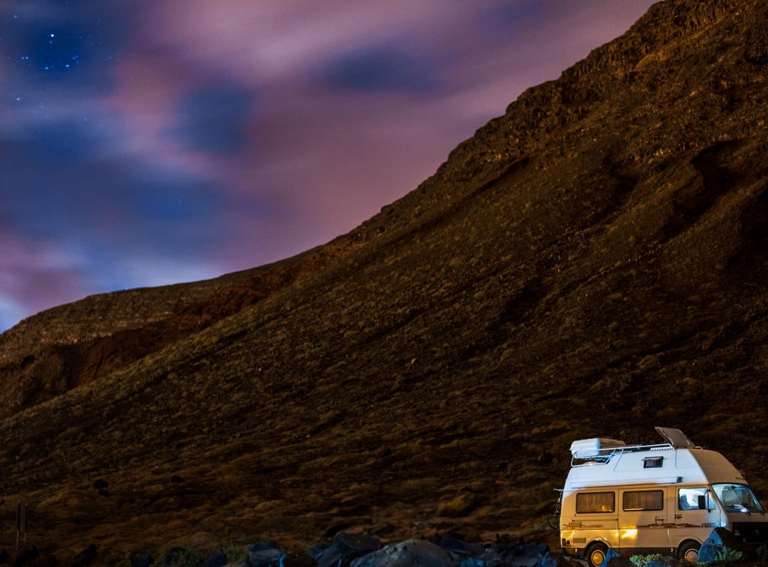 Camper van parked at the base of a rocky mountain.
