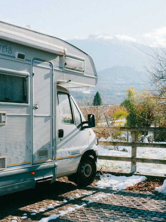White camper van parked with snowy mountains behind