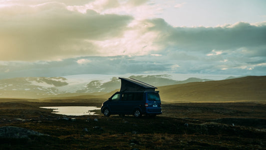 Campervan parked in a vast, cloudy landscape at dusk