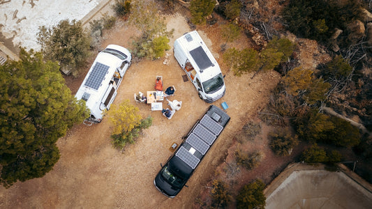 Three camper vans parked in a campsite with people gathered