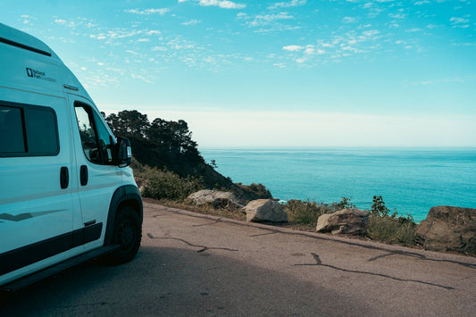 White camper van parked by the ocean road.