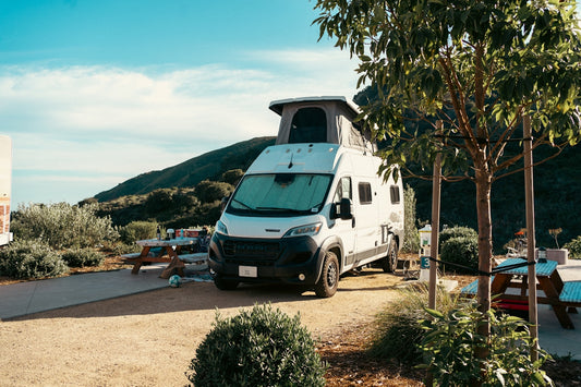 Camper van parked at a campsite with picnic tables.