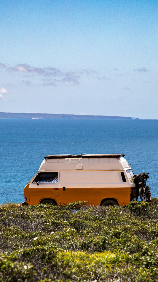 Orange and white camper van parked by the ocean