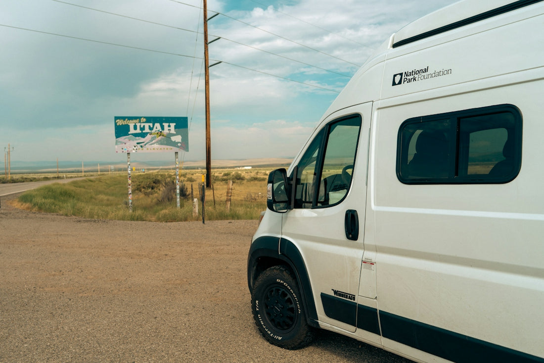 White van parked near a welcome to utah sign